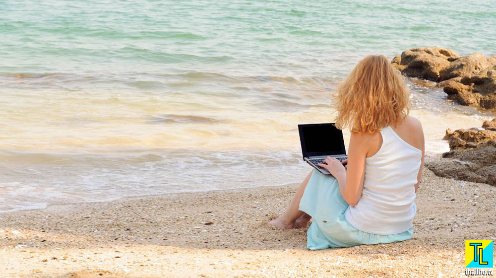 Девушка фрилансер за ноутбуком на пляже